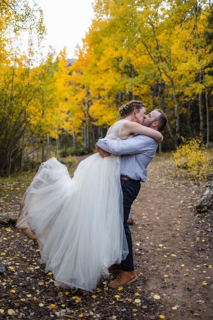 groom picking up bride kissing surrounded by yellow aspens